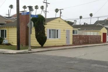 Yellow residential house palm trees street